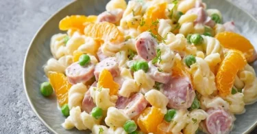 Leckerer Nudelsalat mit Mandarinen und Gemüse in einer Schüssel angerichtet.