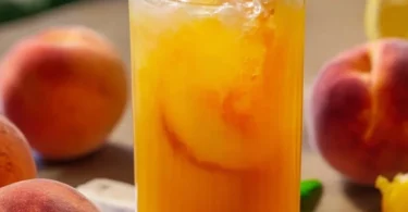 Erfrischende Pfirsich-Limonade in einem Glas mit frischen Pfirsichen